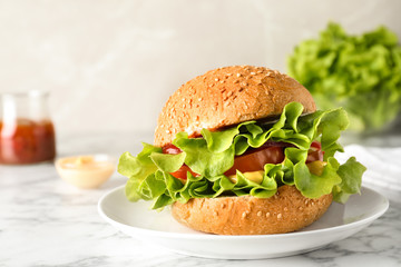 Tasty burger with lettuce and tomato in plate on table. Space for text