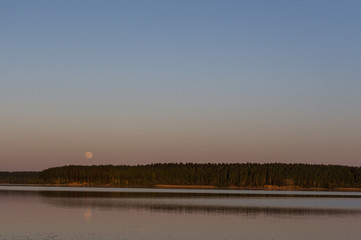 the moon hangs over the lake