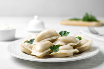 Plate of tasty dumplings served with parsley on table