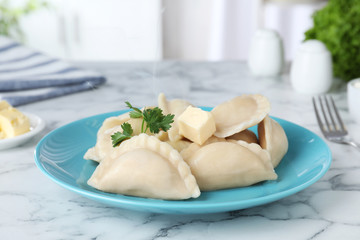 Plate of tasty dumplings served with parsley and butter on table