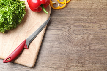 Flat lay composition with sharp knife and space for text on wooden background