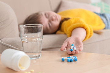 Unconscious little child with pills on sofa at home. Danger of medicament intoxication