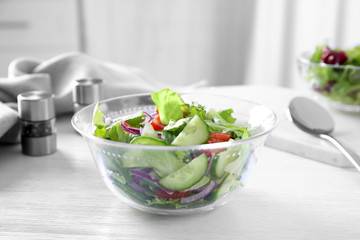 Bowl of tasty salad with cucumber and lettuce on table