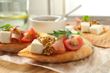 Delicious bruschettas with prosciutto and cheese served on board