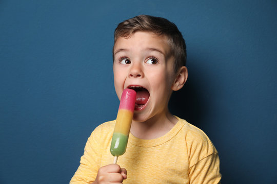 Adorable little boy with delicious ice cream against color background