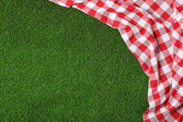 Picnic tablecloth on grass, top view. Space for text