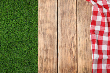 Obraz premium Picnic table with checkered cloth on grass, top view. Space for text