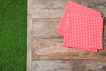 Picnic table with checkered napkins on grass, top view. Space for text