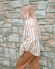 Beautiful girl posing on the street near the brick wall.