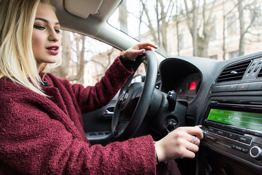 Young Woman Turning Button Of Radio In Car