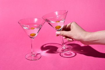 cropped view of woman holding glass of cocktail on pink background