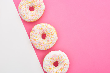 top view of tasty glazed doughnuts on white and pink background with copy space