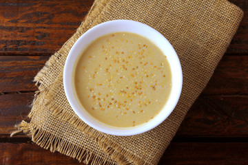 Tahini in ceramic bowl on rustic wooden table- cream or paste made from sesame seeds (sesame) widely used in Middle Eastern cuisine