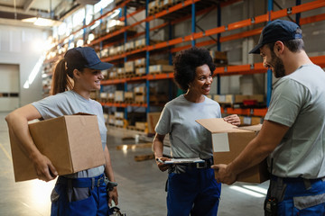 Happy warehouse workers checking cardboard boxes before the shipment.