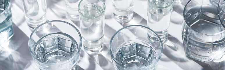 close up view of transparent glasses with water on white background, panoramic shot