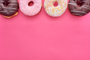 top view of delicious glazed doughnuts on bright pink background with copy space