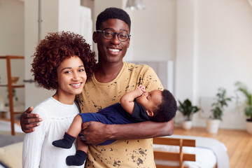 Portrait Of Loving Parents Holding Newborn Baby At Home In Loft Apartment