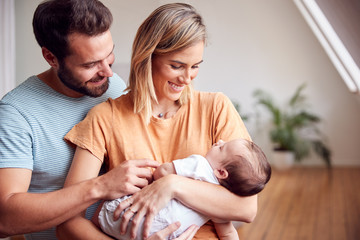 Loving Parents Holding Newborn Baby At Home In Loft Apartment - Powered by Adobe