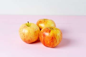 Set of red and yellow apples on pink background