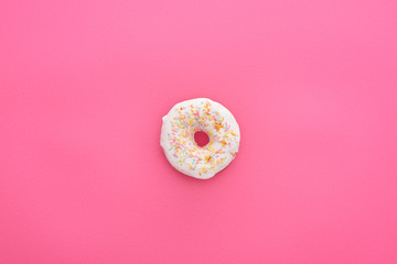 top view of tasty glazed white doughnut with sprinkles on bright pink background