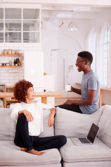 Young Couple Relaxing On Sofa At Home Together And Laughing