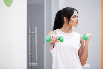 Fitness girl. Teenage woman working out at gym with dumbbells
