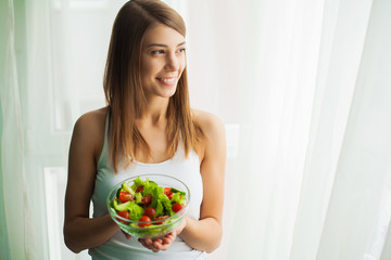 Diet. Young woman eating salad and holding a mixed salad