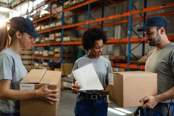 Group of smiling workers checking packages in a warehouse.
