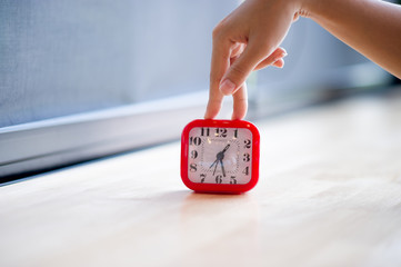 Hand and red alarm clock that shows the alarm at all Every morning, the concept of punctuality