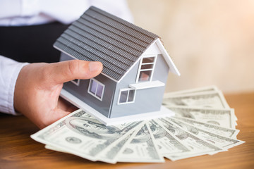 Businessmen holding money and red house models. Real estate loan concept