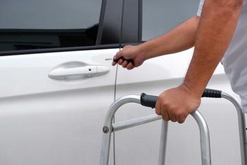 Selective focus of middle-aged man using walker for walk support and using key to open car door in parking area, lifestyle in can help yourself concept
