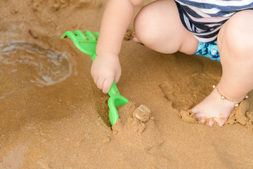 boy playing with shovel toys on the beach in summertime - childhood and summer concept