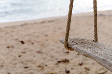 Close-up of Rope wooden swing hanging on tree at topical beach with sunlight in Thailand