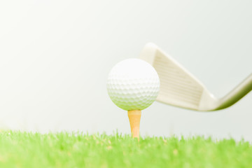 Teeing off with golf club and golf ball on green lawn