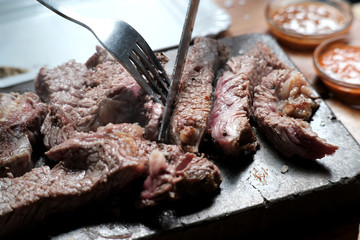 Steak beef on hot lava stone. The rib eye steak was sliced into pieces by knife cooking on the hot...