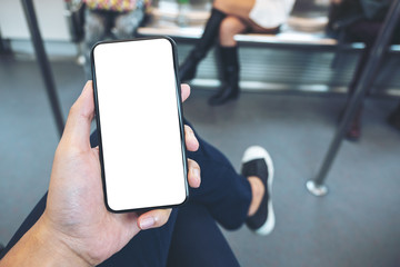 Mockup image of hand holding white mobile phone with blank black screen in subway