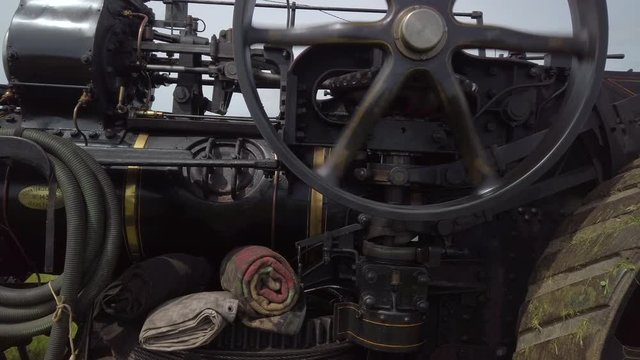 Close-up of the side of a black vintage traction engine in operation.
