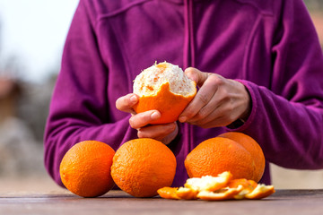 Woman peels oranges from peel.