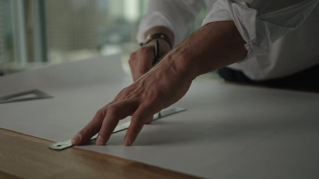 Businessman traces a project in office with view on downtown and skyscrapers. Architect's work process.