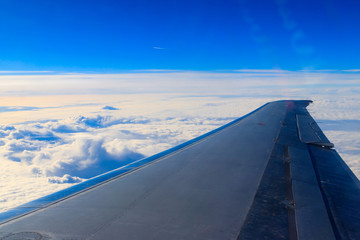 Fototapeta na wymiar Wing of airplane flying above the clouds in the blue sky