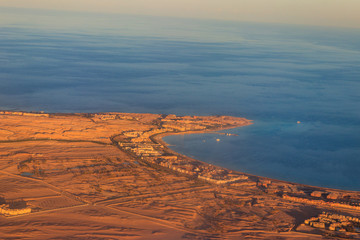 Aerial view on Red sea, Arabian desert and touristic resort near Hurghada, Egypt. View from airplane