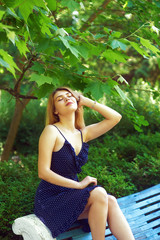 Portrait of a young girl in a city Park . A woman in a summer dress resting sitting on a bench