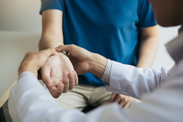 Physical therapist checks the patient wrist by pressing the wrist bone in clinic room.