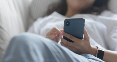 Woman use of smart phone and lying down on sofa