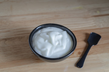 Natural homemade plain organic yogurt in bowl on wood texture background