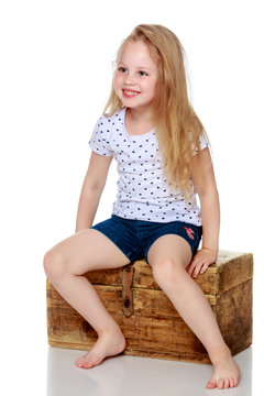 A little girl is sitting on a wooden box.