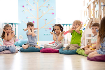Kids seating on floor and show gestures making task in daycare