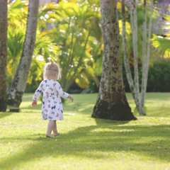  Adorable baby girl in the beautiful tropical park, candid outdoor portrait