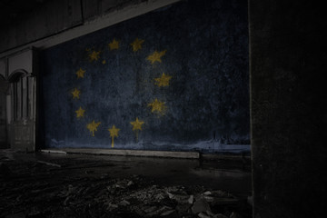 painted flag of european union on the dirty old wall in an abandoned ruined house.