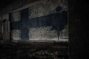 painted flag of finland on the dirty old wall in an abandoned ruined house.